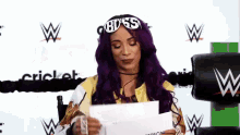 a woman with purple hair is holding a piece of paper and wearing a headband that says boss .