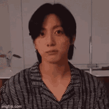 a close up of a person 's face in a kitchen wearing a black and white striped shirt .