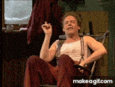a man is sitting in a chair and smoking a cigarette with make a gif.com in the corner