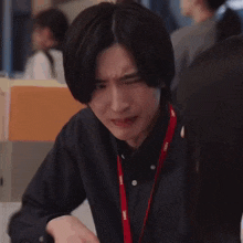 a man is making a funny face while sitting at a table with his hands together .