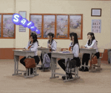 a group of girls sit at desks in a classroom with a blue balloon that says sa