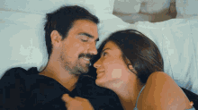 a man and a woman are laying in bed looking at each other and smiling