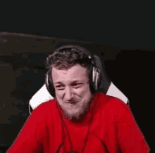 a man wearing headphones and a red shirt is clapping his hands .