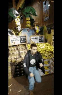 a man dancing in front of a sign that says pineapple for 2.99 and bananas for 59
