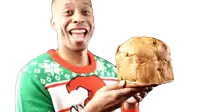 a man wearing an ugly christmas sweater is holding a loaf of bread in his hands