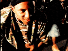 a man wearing a camouflage shirt and a hat is smiling