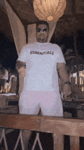 a man wearing a white essentials t-shirt and pink shorts