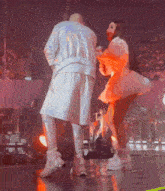 a man and a woman are dancing on a stage with a crowd in the background