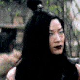 a woman with long black hair is wearing a black top