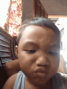 a baby making a funny face in front of a curtain