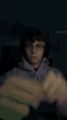 a young man wearing glasses and headphones is holding something in his fist