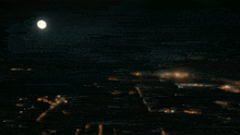 a full moon is visible in the night sky above a city