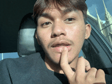 a man with a mustache is sitting in a car with his finger on his lips