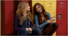 two girls are sitting next to each other in front of school lockers .
