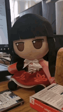 a stuffed doll sits on a desk next to a box of tablets