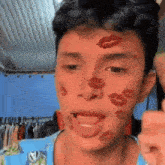a young man with red lips painted on his face is giving a thumbs up .