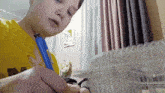a boy in a yellow shirt is holding a blue pen