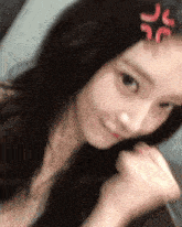 a close up of a woman 's face with a red angry face on her forehead .