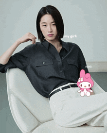 a woman in a black shirt sits in a chair next to a pink my girl