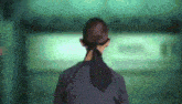 a woman in a ponytail is standing in a room with a green background .