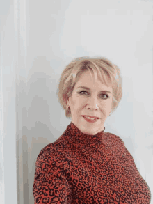 a woman wearing a leopard print top is smiling