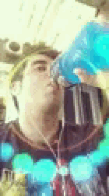 a man is drinking a blue drink from a bottle .