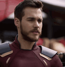 a man with a beard is wearing a red and black superhero costume