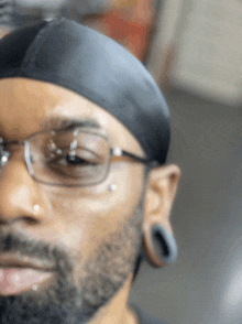 a man with a beard wearing glasses and ear plugs