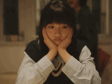 a young girl with her hands on her face looks sad