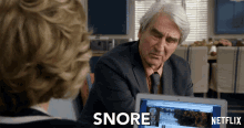 a man in a suit and tie sits in front of a laptop with the words " snore " on the screen