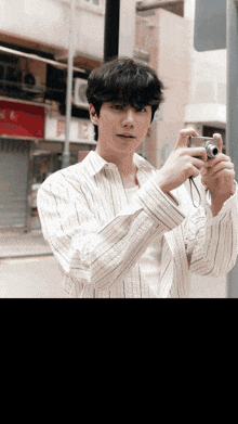 a man in a striped shirt is taking a picture with his camera