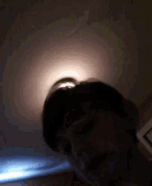 a person 's head is visible in a dark room with a light shining on it