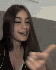 a woman with long hair is smiling and making a funny face .