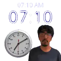 a man wearing glasses stands in front of a clock that reads 7:10