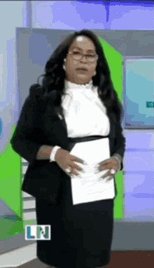 a woman in a suit is holding a piece of paper with the letters ln on the bottom right