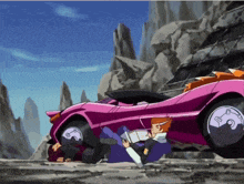 a man is laying on the ground near a pink car