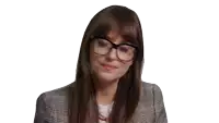 a woman wearing glasses and a plaid jacket looks at the camera