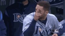 a man wearing a rays jersey wipes his nose