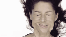 a woman making a funny face with her eyes closed and her hair blowing in the wind