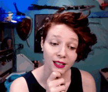 a woman with red hair and pink lipstick is making a face
