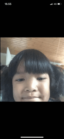 a little girl is taking a picture of herself on a cell phone with the time of 18.55