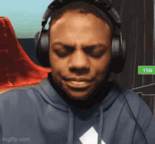 a man wearing headphones and a hoodie is making a face .