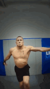 a shirtless man with a tattoo on his chest is jumping in a gym