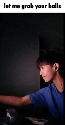 a young man in a blue shirt is standing in a dark room with headphones on .