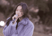a woman singing into a microphone with once written on the bottom right