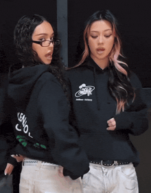 two women wearing black hoodies one of which has the word leno on it