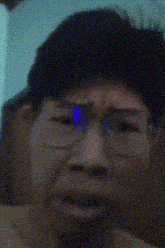 a close up of a person wearing glasses with a blue light reflected in them