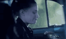 a woman is sitting in the driver 's seat of a car with her eyes closed .