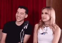a man and a woman are sitting next to each other in front of a microphone .