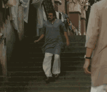 a man walking down a set of stairs with clothes hanging on the wall behind him